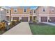 Tan three-story townhouses with brown garages, landscaping, and a paved driveway at 1336 Chelsea Dr, Davenport, FL 33897