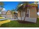 Tan house with a large window, palm trees, and a well-maintained lawn at 3571 Maple Ridge Loop, Kissimmee, FL 34741