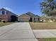Tan one-story house with a two-car garage and landscaping at 102 Lake Tracy Ct, Haines City, FL 33844