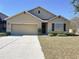 Tan one-story house with a two-car garage and landscaping at 102 Lake Tracy Ct, Haines City, FL 33844