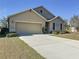 Tan one-story house with a two-car garage and landscaping at 102 Lake Tracy Ct, Haines City, FL 33844
