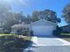 House exterior featuring a light blue vinyl-sided home with a two-car garage and landscaped lawn at 5062 El Destino Dr, Leesburg, FL 34748