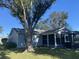 Backyard view of the house with large tree and screened porch at 5062 El Destino Dr, Leesburg, FL 34748