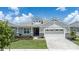 One-story home with gray siding, a two-car garage, and a landscaped lawn at 1790 Flourish Ave, Kissimmee, FL 34744