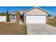 Tan house with red door, white garage door, and landscaping at 825 Desmoines Pl, Kissimmee, FL 34759