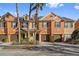Orange townhouses with brown garages, palm trees, and lush landscaping at 879 Assembly Ct, Reunion, FL 34747
