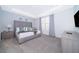 Main bedroom with gray upholstered bed, nightstands, and a large window at 2166 Fleming Mist Pl, Kissimmee, FL 34747