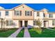 Tan two-story townhome with dark gray shutters and doors, a paved walkway, and well-manicured lawn at 2166 Fleming Mist Pl, Kissimmee, FL 34747