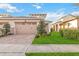 Tan two-car garage home with brick paver driveway and landscaping at 2482 Yellow Brick Rd, St Cloud, FL 34772