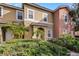 Two-story townhome with tan and peach exterior, and lush landscaping at 3083 Yellow Lantana Ln, Kissimmee, FL 34747