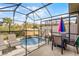 Screened-in pool area with patio furniture and a colorful umbrella at 3083 Yellow Lantana Ln, Kissimmee, FL 34747