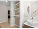 Small powder room with pedestal sink and open shelving at 8610 Tallfield Ave, Orlando, FL 32832