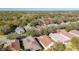 Aerial view of neighborhood with solar panels, trees, and a variety of roof colors at 105 Flame Vine Way, Groveland, FL 34736