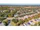 Aerial view of a neighborhood showing rooftops, trees, and a small pond at 105 Flame Vine Way, Groveland, FL 34736