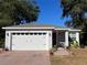 White house with a red door, two-car garage, and a brick paved driveway at 1493 Park Dr, Casselberry, FL 32707