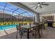 Screened-in lanai with outdoor dining table, gas grill, and a view of the pool at 4141 Lana Ave, Davenport, FL 33897
