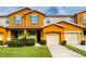 Inviting two-story townhome with orange exterior, two-car garage, and well-manicured lawn at 5107 Killarney Way, Kissimmee, FL 34746