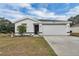 White house with black accents, two-car garage, and landscaped lawn at 608 Gila Dr, Kissimmee, FL 34759