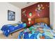 Toy Story themed bedroom with twin beds, nightstands, and a red accent wall at 8984 Silver Pl, Kissimmee, FL 34747