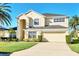 Two-story house with beige exterior, two-car garage, and manicured lawn at 1020 Golf Course Pkwy, Davenport, FL 33837