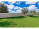 Backyard view showcasing a privacy wall, lush green lawn, and young trees at 3896 Grassland Dr, Orlando, FL 32824
