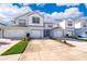 Inviting two-story townhome with a white and gray exterior, attached garage, and lush landscaping at 3896 Grassland Dr, Orlando, FL 32824