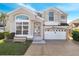 Two-story house with a large front yard, a two-car garage, and a brick driveway at 2430 Berkshire Ct, Kissimmee, FL 34746