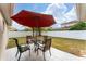 Backyard patio with seating area under a red umbrella, fenced yard, and landscaping at 622 Parakeet Ct, Kissimmee, FL 34759