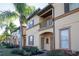 Townhome exterior showcasing the entrance, landscaping, and palm trees at 733 Calabria Ave, Davenport, FL 33897