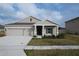 Tan house with gray roof, two-car garage, and landscaping at 420 Watusi Way, Saint Cloud, FL 34772