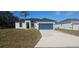Single-story house with a teal garage door and landscaped lawn at 605 Raven Ct, Kissimmee, FL 34759