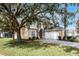 Two-story house with tan exterior, white garage door, and large tree to the left at 673 Copeland Dr, Haines City, FL 33844