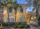 Yellow two-story townhome with white trim, lush landscaping, and a designated parking spot at 8535 Bay Lilly Loop, Kissimmee, FL 34747