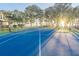 Blue tennis court, surrounded by trees, great for outdoor games at 1465 Riviera Dr, Kissimmee, FL 34744