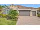 House exterior featuring gray walls, brown tile roof, and a two-car garage at 681 San Joaquin Rd, Poinciana, FL 34759