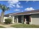 Exterior view of a light green house with a brown roof, palm trees, and a landscaped yard at 34 Pine Island Cir, Kissimmee, FL 34743