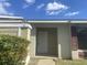 Front entrance of a light green house with a white door and dark red shutters at 34 Pine Island Cir, Kissimmee, FL 34743