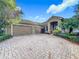 House with paver driveway, two-car garage, and manicured landscaping at 542 Viterra Ct, Kissimmee, FL 34759