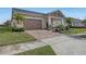 Tan house with palm trees, a two-car garage, and a brick driveway at 5043 Vantage Ct, St Cloud, FL 34772