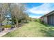 Large grassy backyard with mature trees, stone pathway, and lake view at 521 Milano Rd, Kissimmee, FL 34759