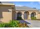 Tan house with arched entryway, three-car garage, and manicured landscaping at 1280 Osprey Landing Dr, Lakeland, FL 33813