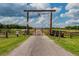 Long driveway entrance with wooden gate and star compass at 6225, 6229 Deen Still Rd, Lakeland, FL 33809