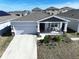One-story house with gray roof, attached garage, and driveway at 590 Tanaro Ln, Haines City, FL 33844