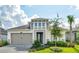 Two-story house with a gray and beige exterior, landscaped lawn, and a two-car garage at 128 Mosaic Blvd, Daytona Beach, FL 32124