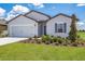Two-car garage and front entrance of a charming light gray house with landscaping at 4270 Sw 143Rd Lane Rd, Ocala, FL 34473