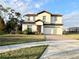 Two-story house with light beige walls, brown roof, and a two car garage at 210 Kenny Blvd, Haines City, FL 33844