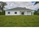 Back of house with covered patio and grassy yard at 7811 Red Grange Blvd, Indian Lake Estates, FL 33855