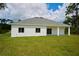 Back of house with covered patio and grassy yard at 7811 Red Grange Blvd, Indian Lake Estates, FL 33855