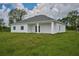 Back of house, showcasing covered patio and yard at 7811 Red Grange Blvd, Indian Lake Estates, FL 33855