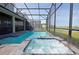 Enclosed pool and spa with lake view; lounge chairs and screened enclosure at 2857 Bookmark Dr, Kissimmee, FL 34746